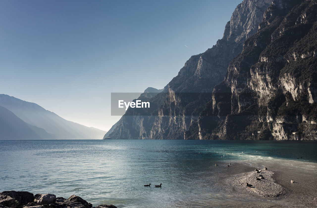 Scenic view of sea and mountains against clear sky