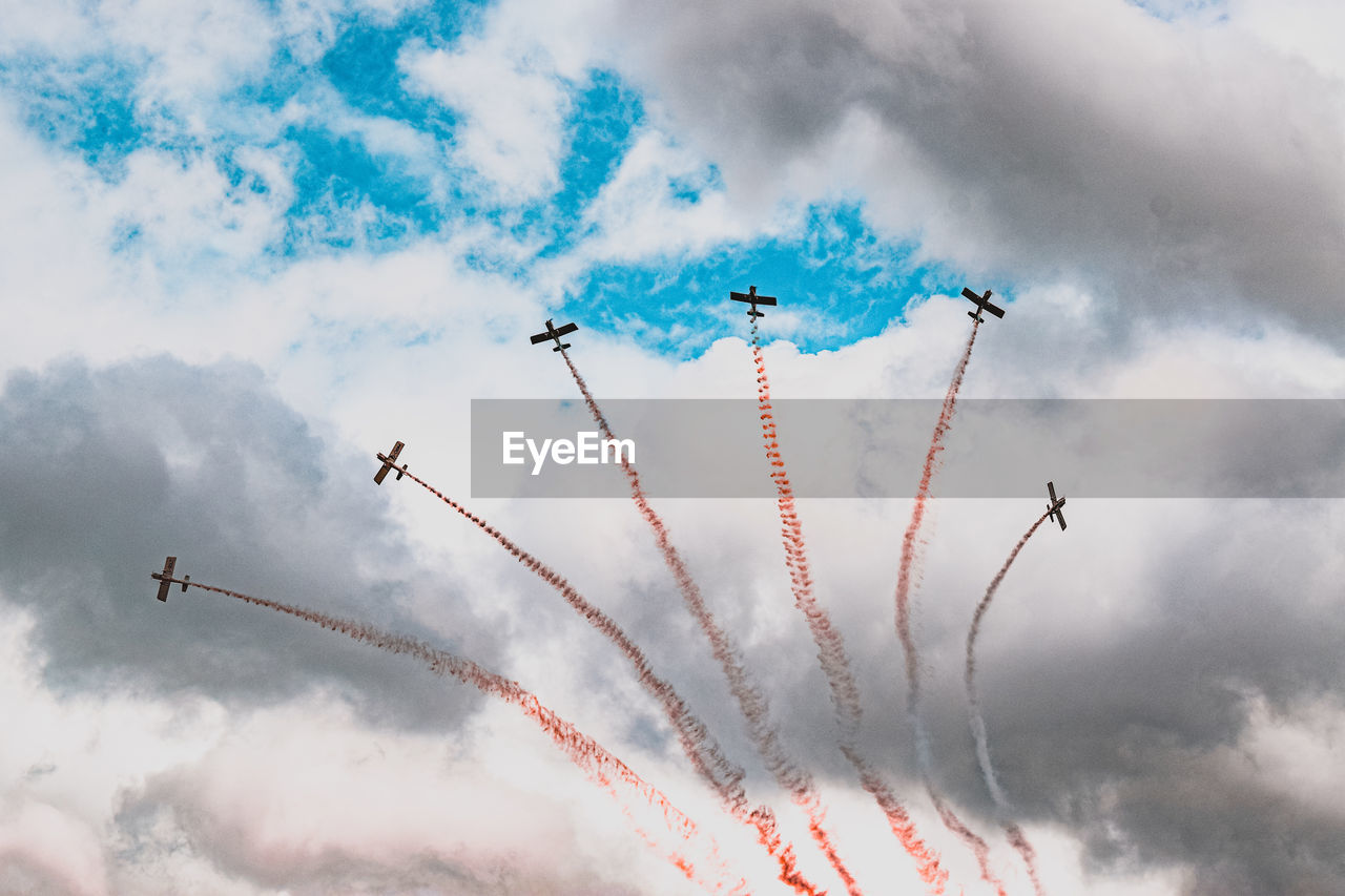 LOW ANGLE VIEW OF AIRSHOW AND AIRPLANE FLYING AGAINST SKY