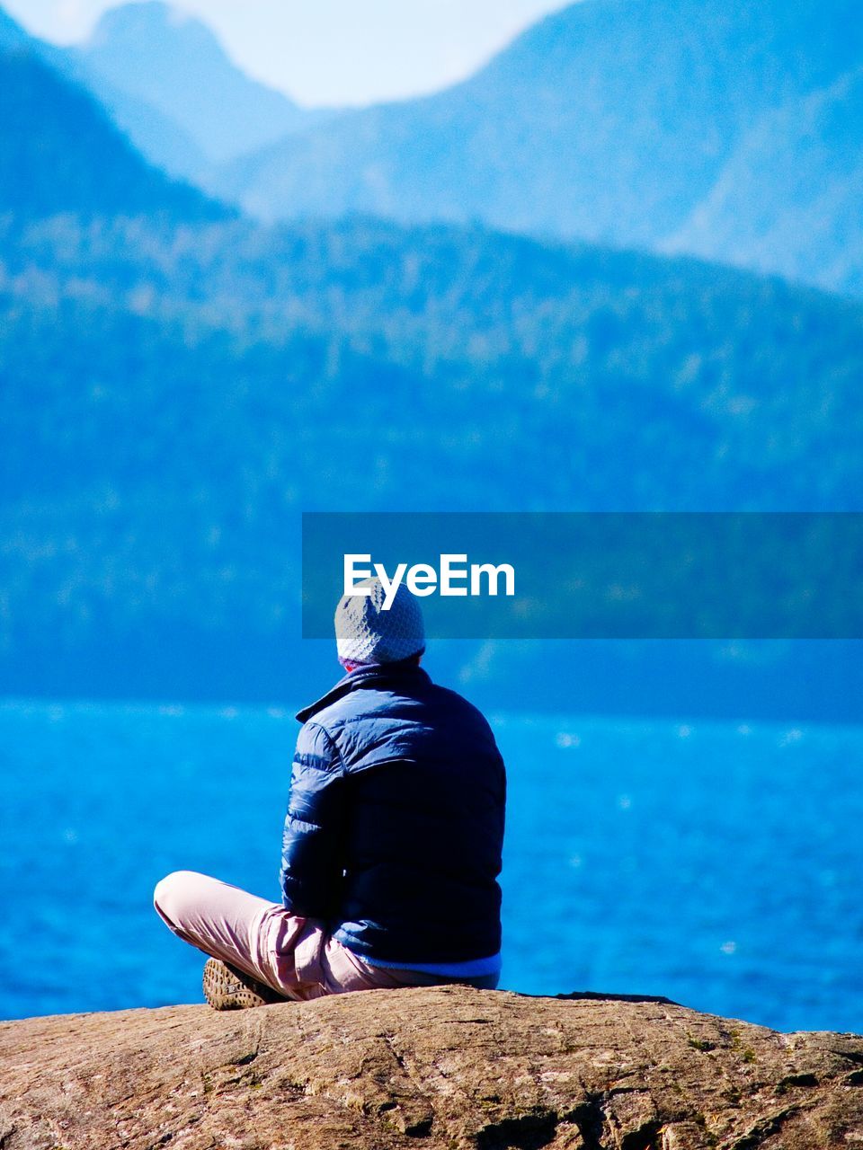 Rear view of a man overlooking calm lake