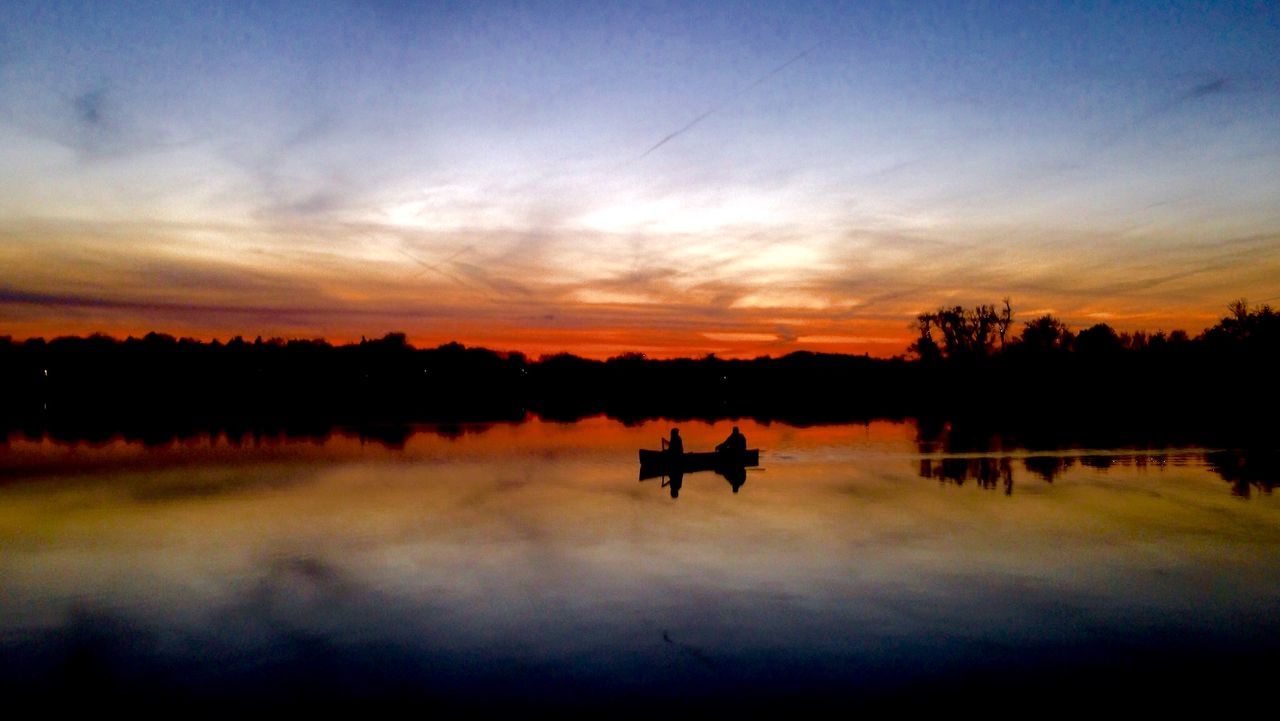 Silhouette of two people boating in lake