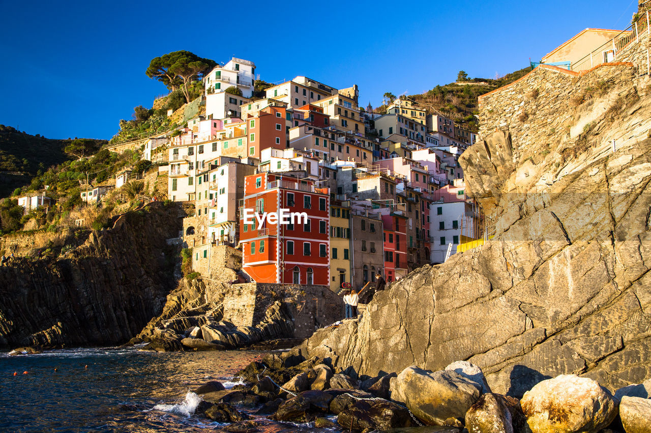 Italian village riomaggiore against cliff and sea during sunset, cinque terre, la spezia, italy