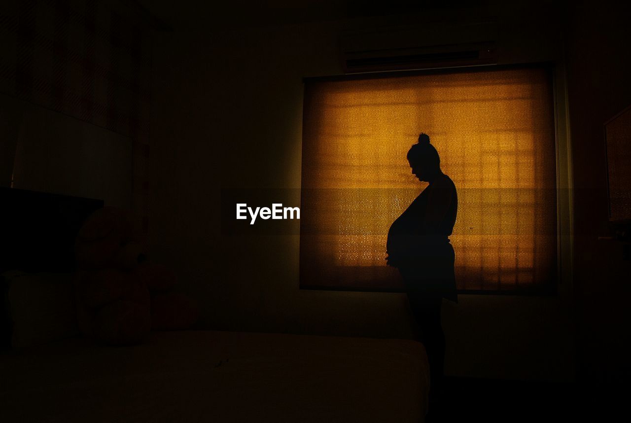 SILHOUETTE WOMAN STANDING AGAINST WINDOW IN BUILDING