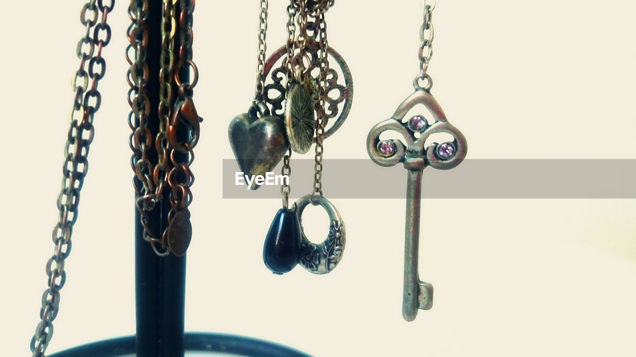 Close-up of jewelry with key against white background