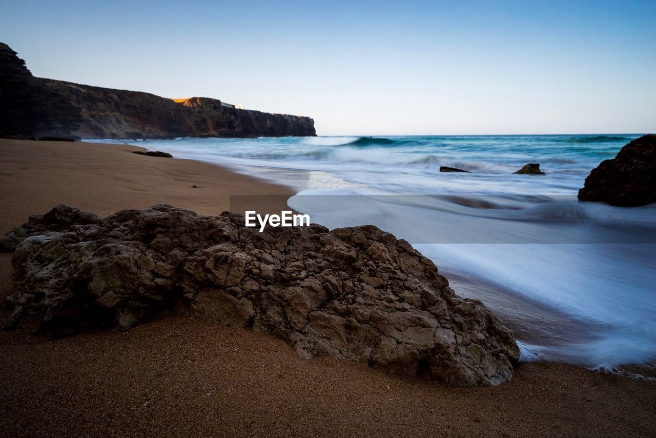 Rock formation at beach against clear sky