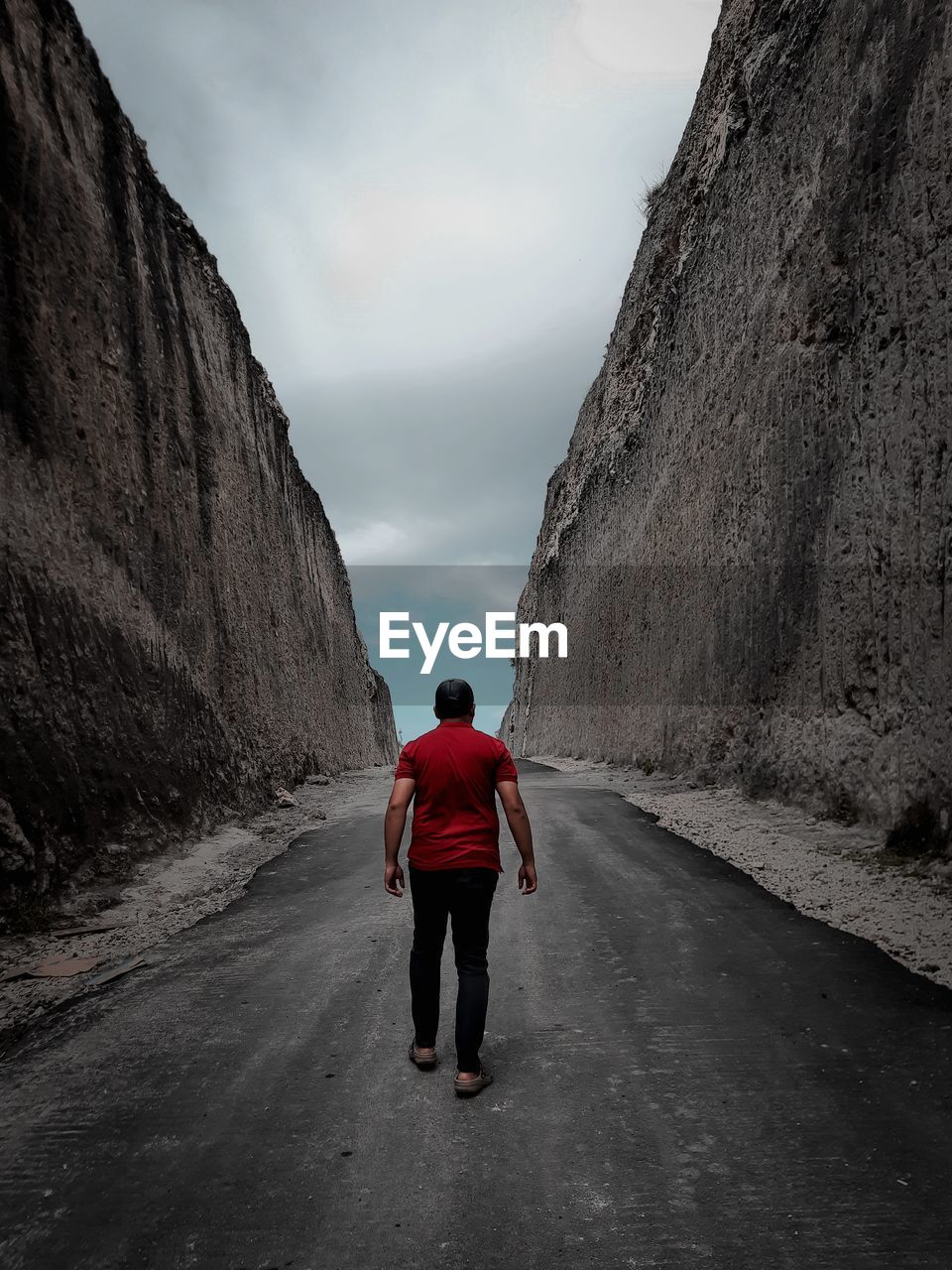 Rear view of man walking on road against sky