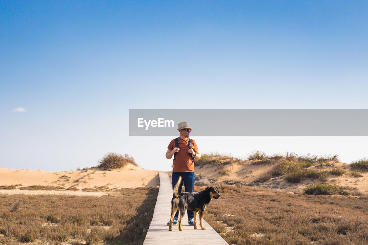 MAN WITH DOG AGAINST SKY