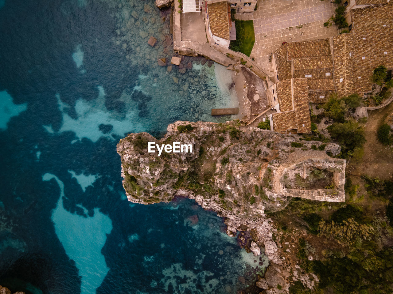 HIGH ANGLE VIEW OF TURTLE IN SEA BY OLD BUILDING