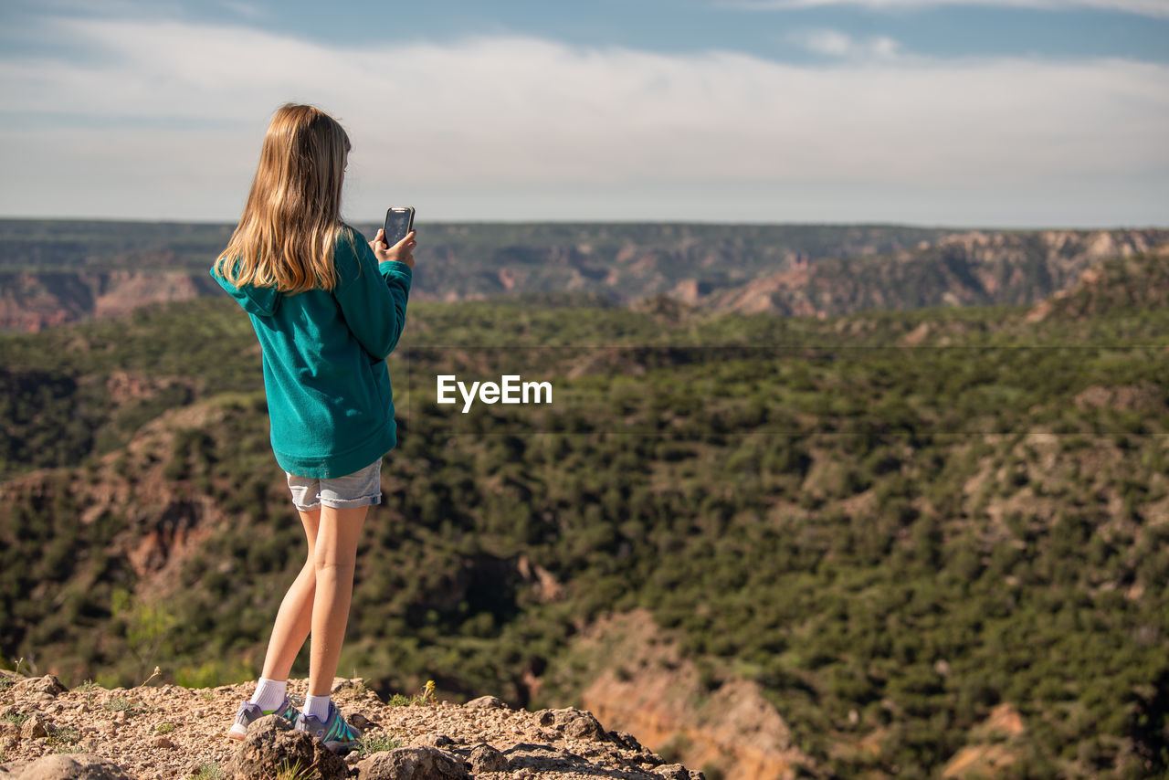 Girl takes photos of canyon with her mobile phone