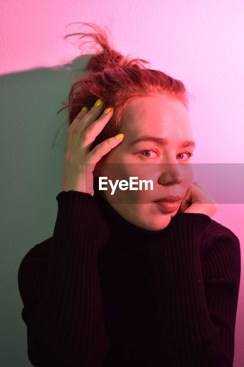 Portrait of beautiful young woman against pink background