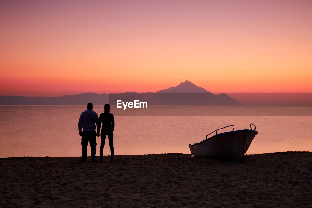 People on beach against sky during sunset