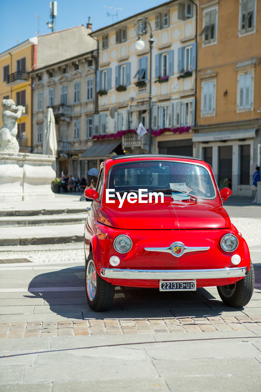 VINTAGE CAR ON STREET BY BUILDINGS