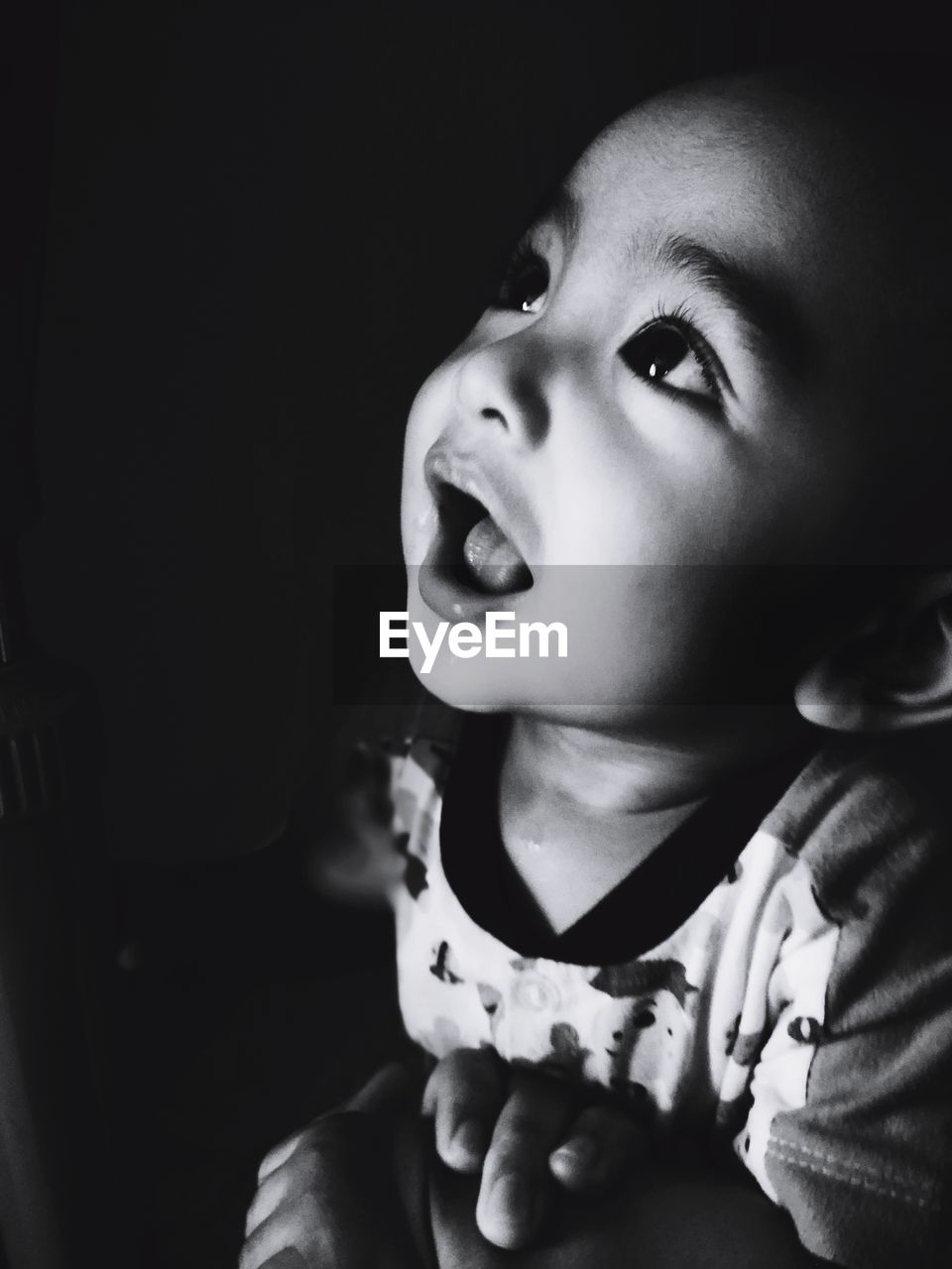 Close-up of baby boy looking up in darkroom