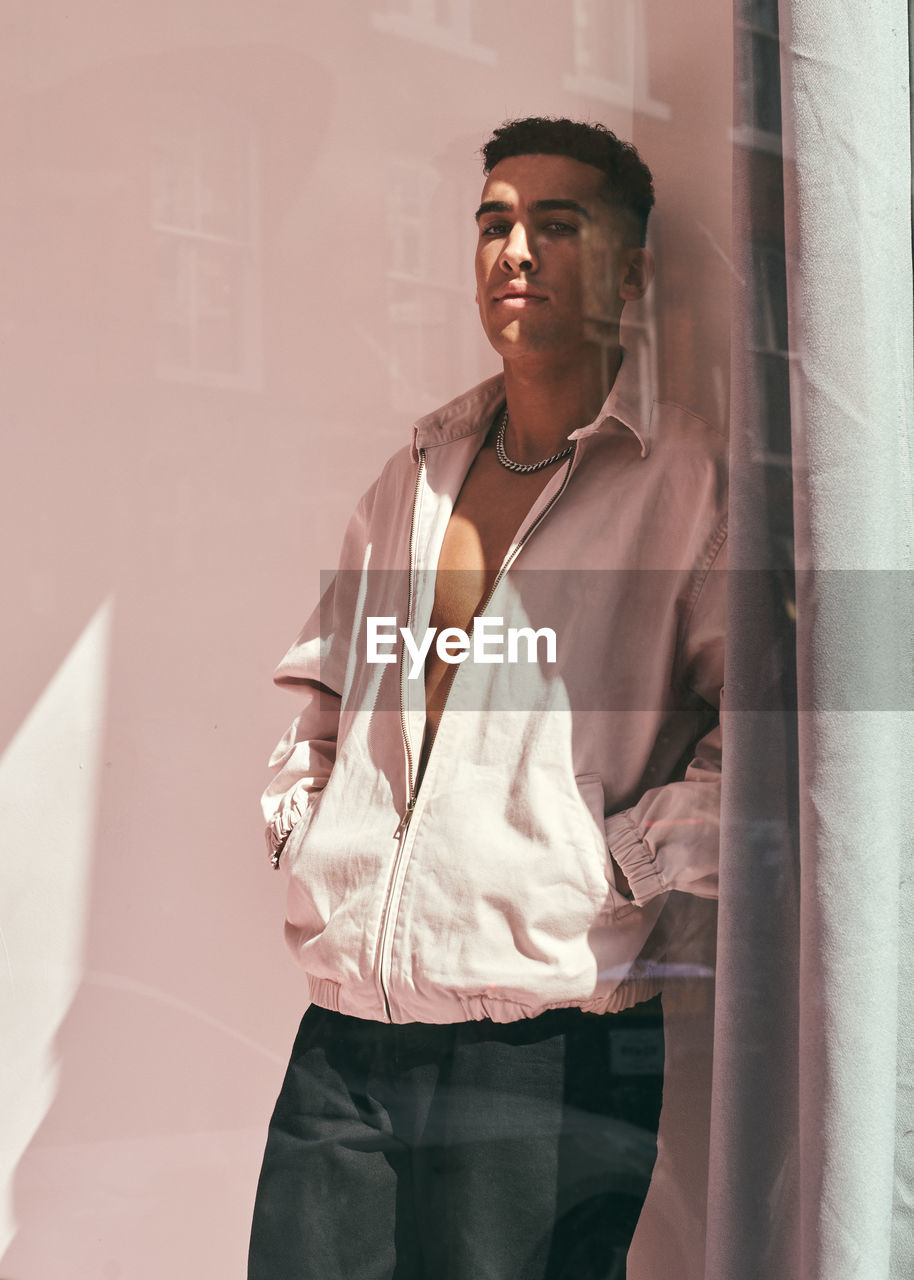 Portrait of young man while standing against wall