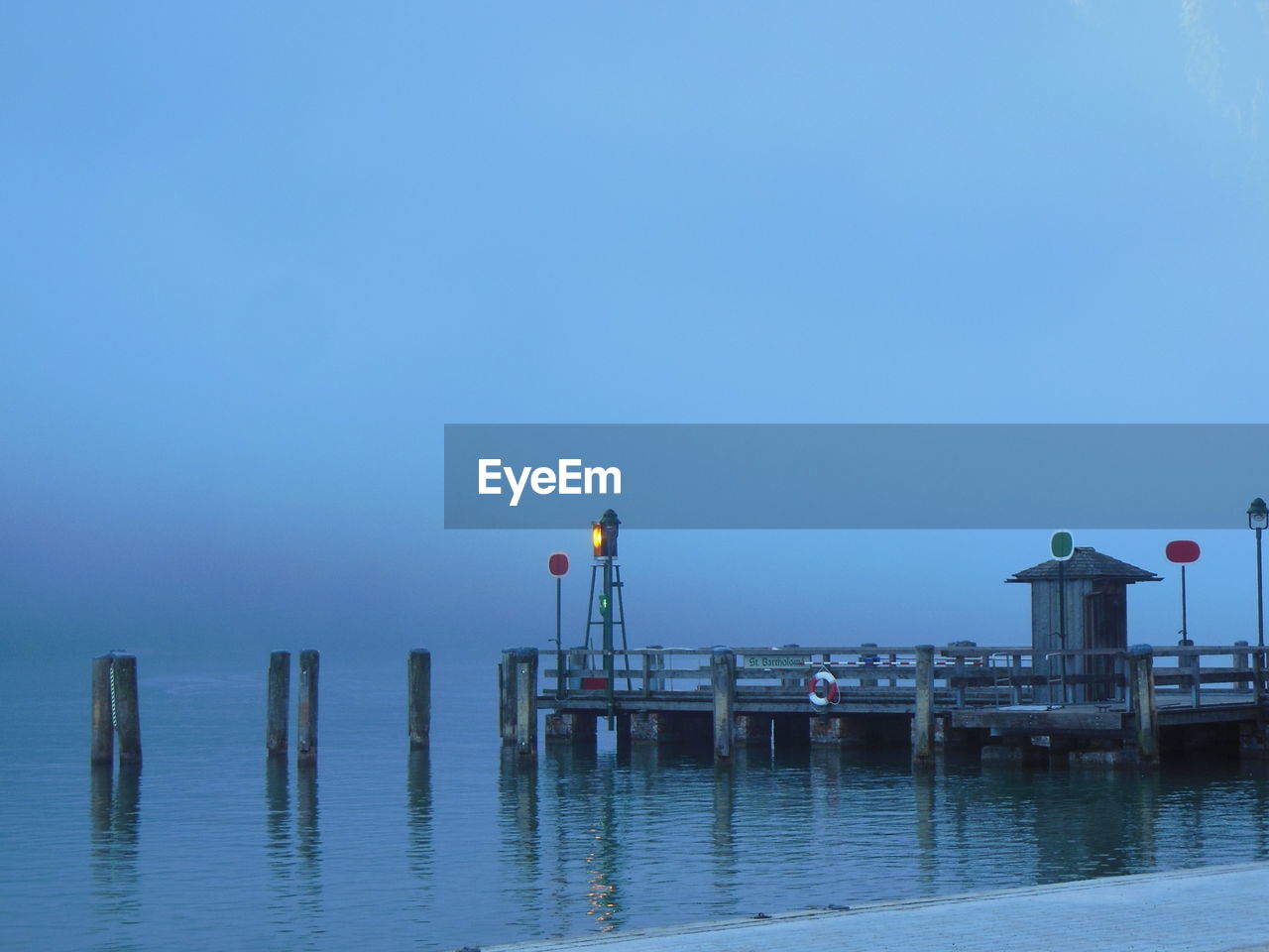 Pier over river against sky during foggy weather