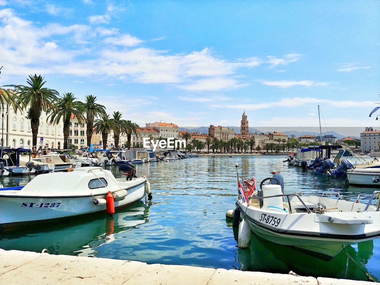 BOATS MOORED IN HARBOR AGAINST SKY