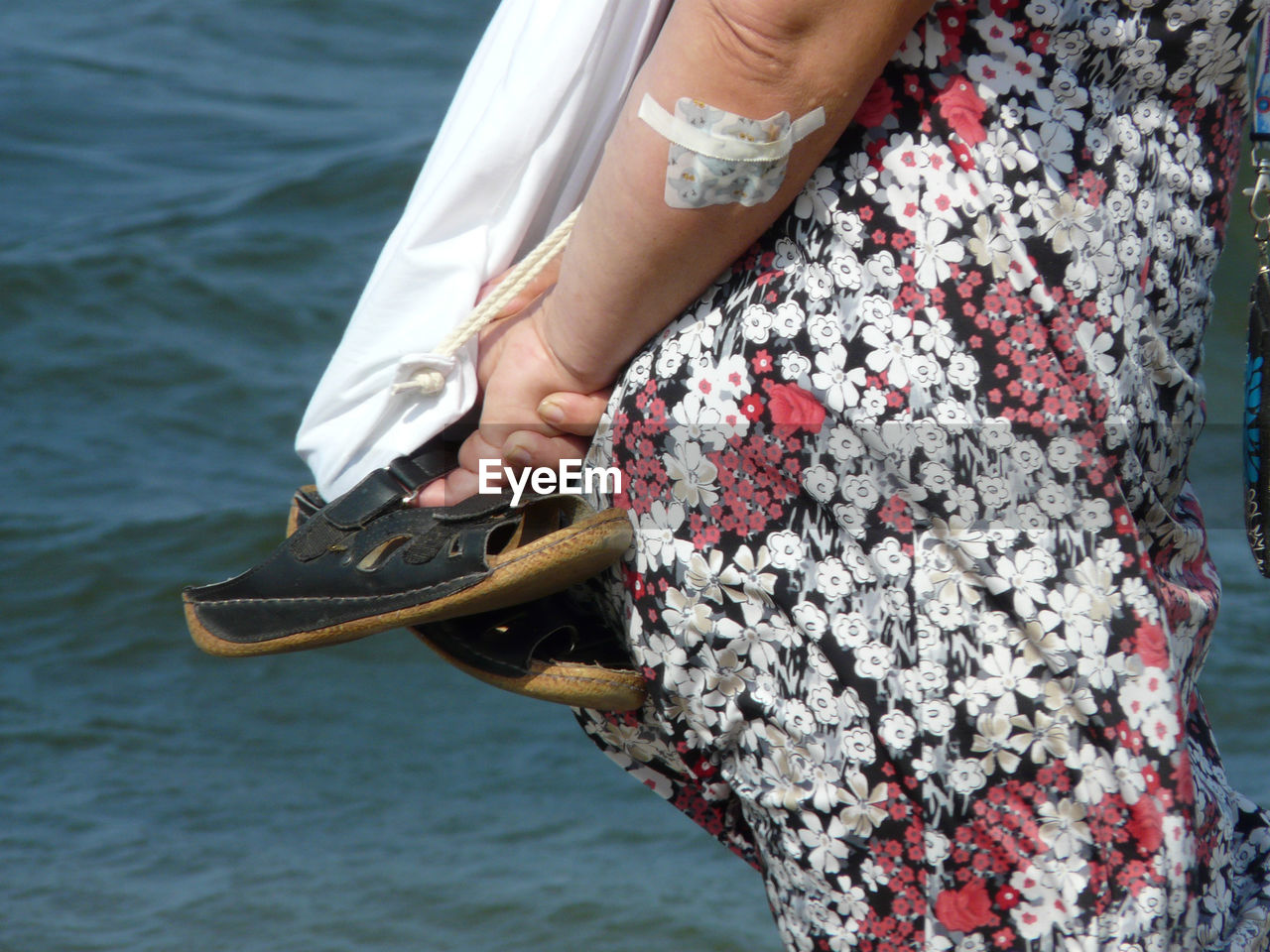 LOW SECTION OF WOMAN WITH UMBRELLA ON SEA