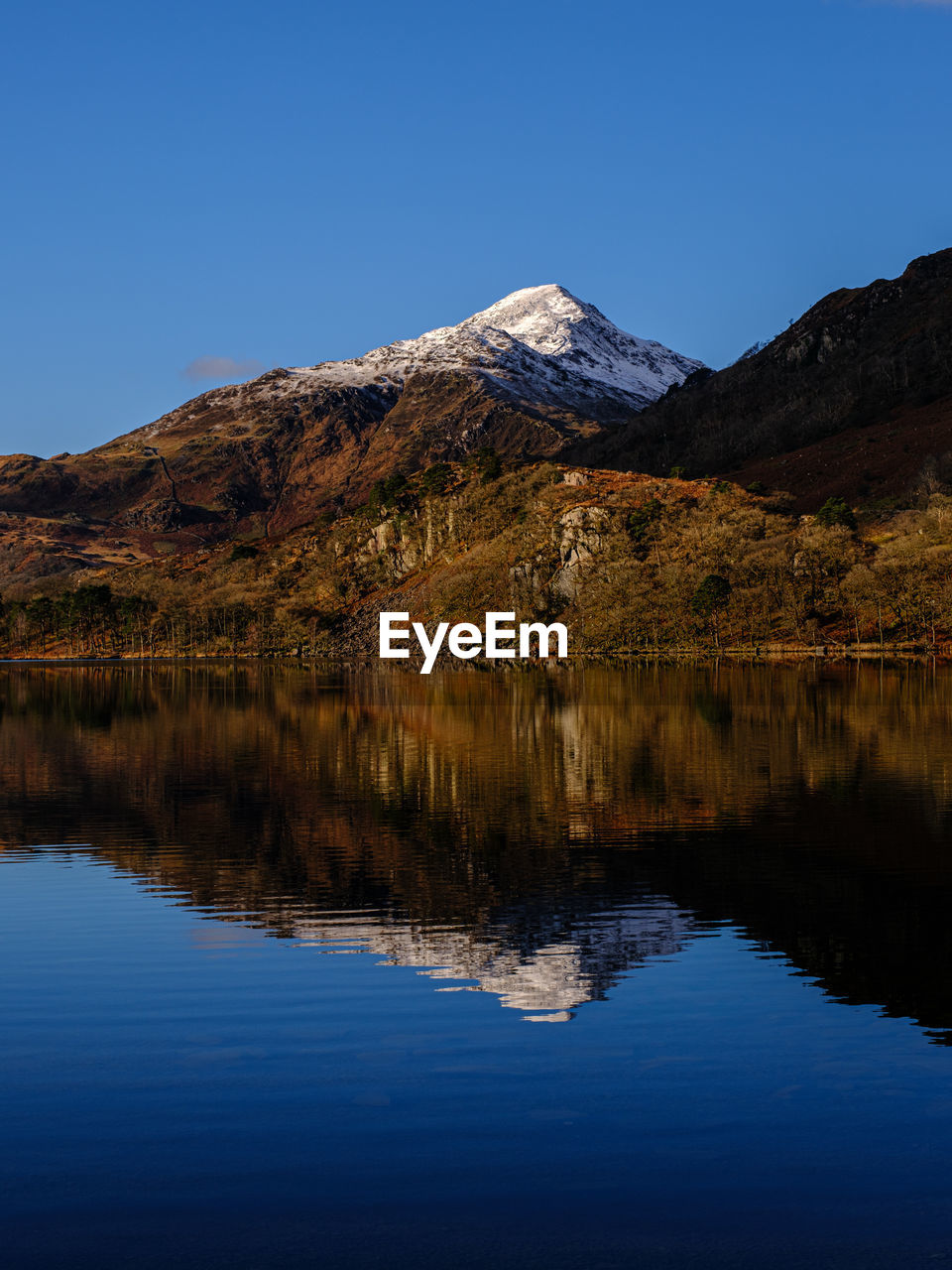 Perfect reflection of snow covered mountains in a lake in snowdonia national park, north wales