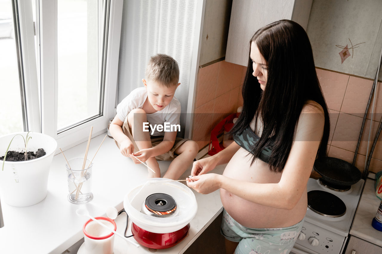 High angle view of pregnant woman with son preparing cotton candies at home