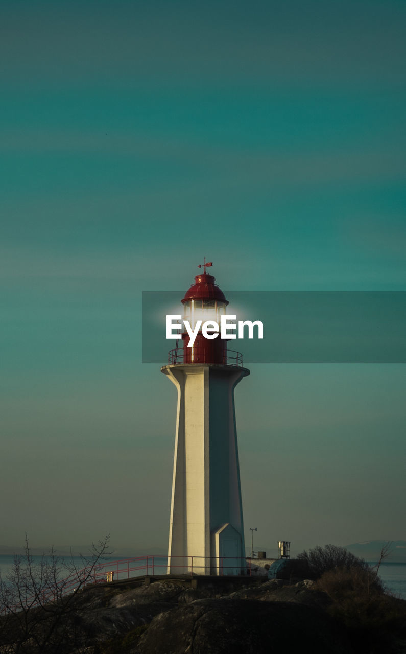 lighthouse by sea against clear sky