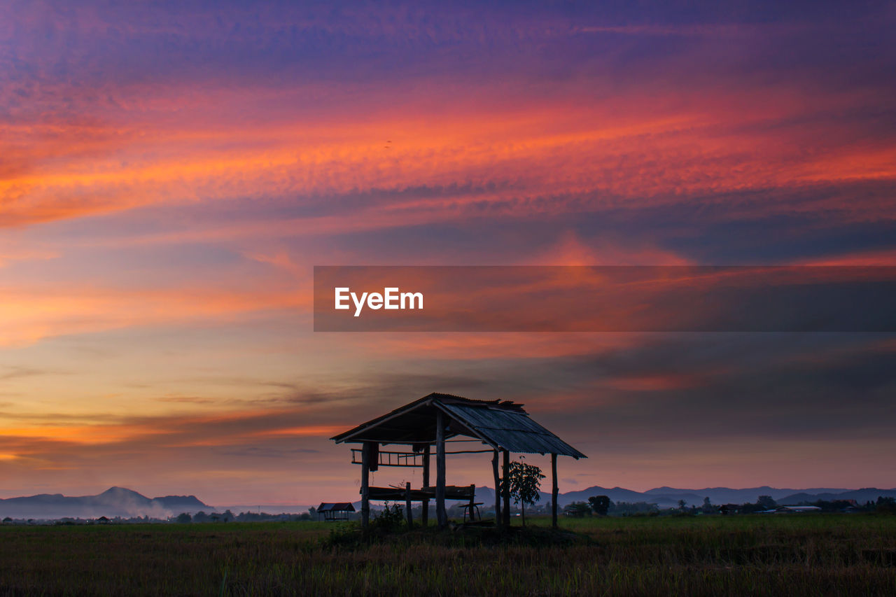 Built structure on field against sky at sunset