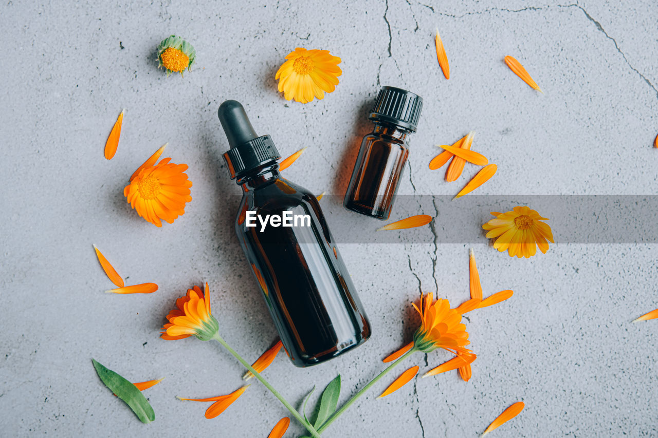 Top view of glass bottles of calendula essential oil with fresh marigold orange 