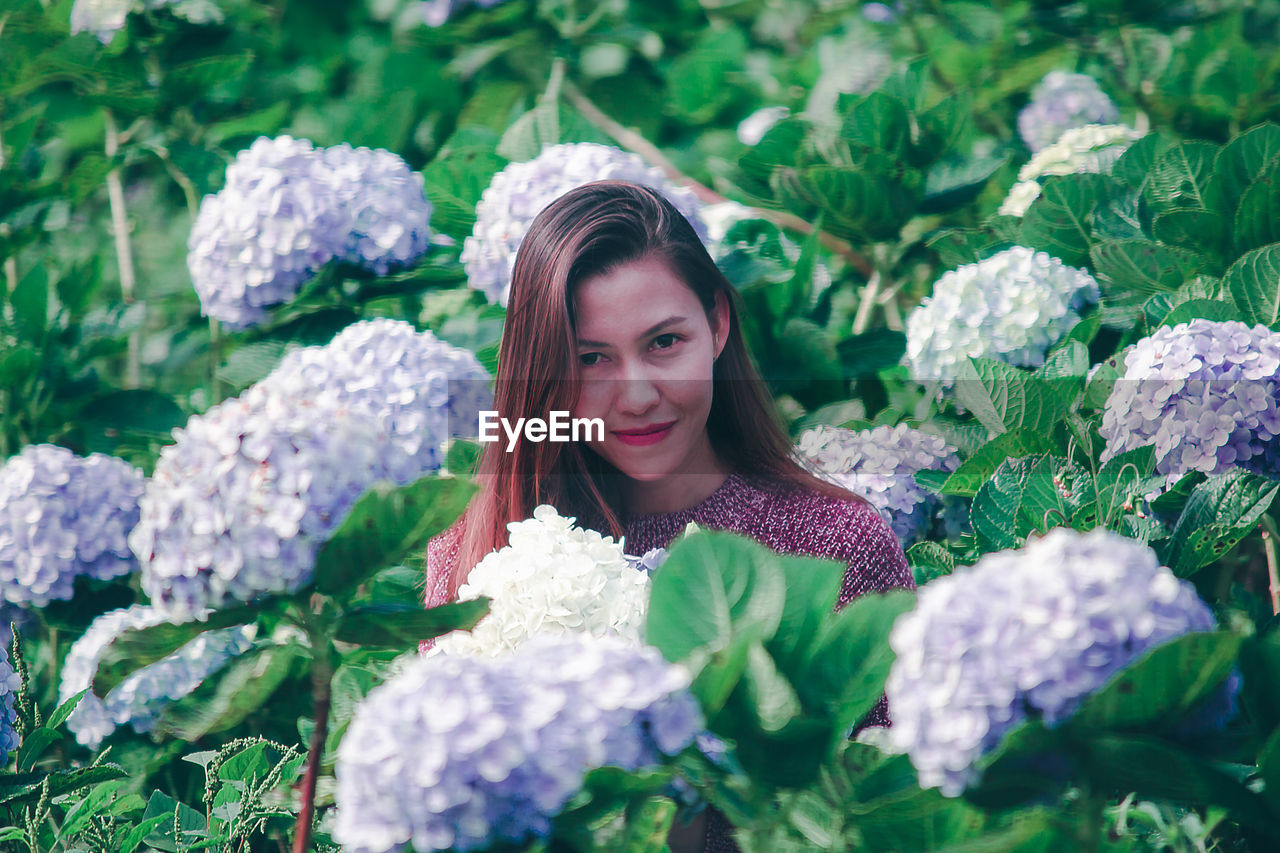 Portrait of smiling woman by flowering plants