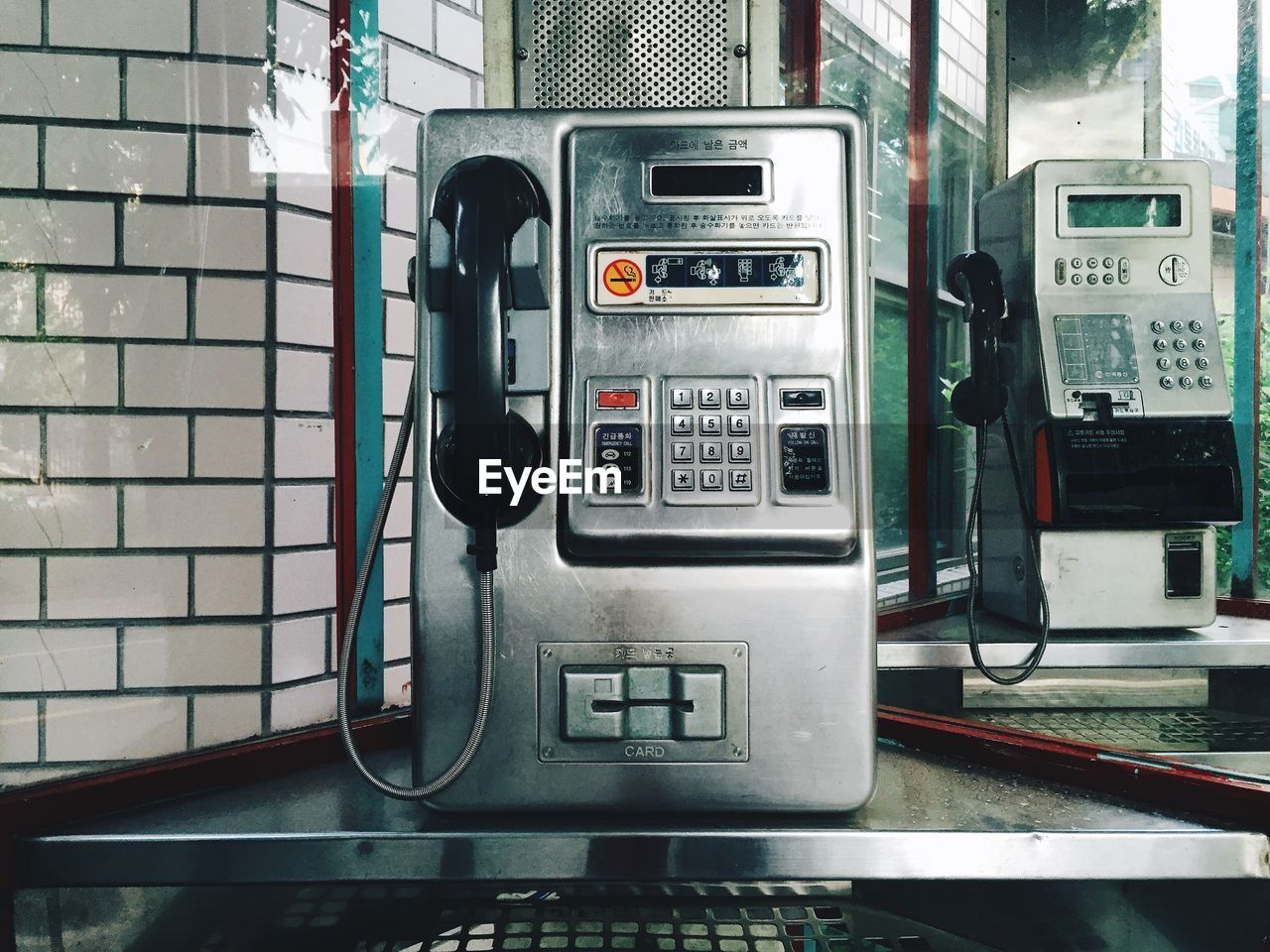 Close-up of pay phones seen through glass