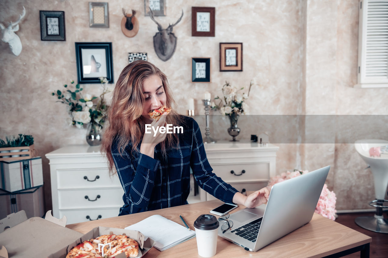 WOMAN USING MOBILE PHONE WHILE SITTING IN RESTAURANT