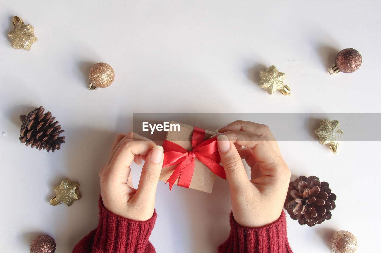 cropped hand of woman holding christmas decorations on table