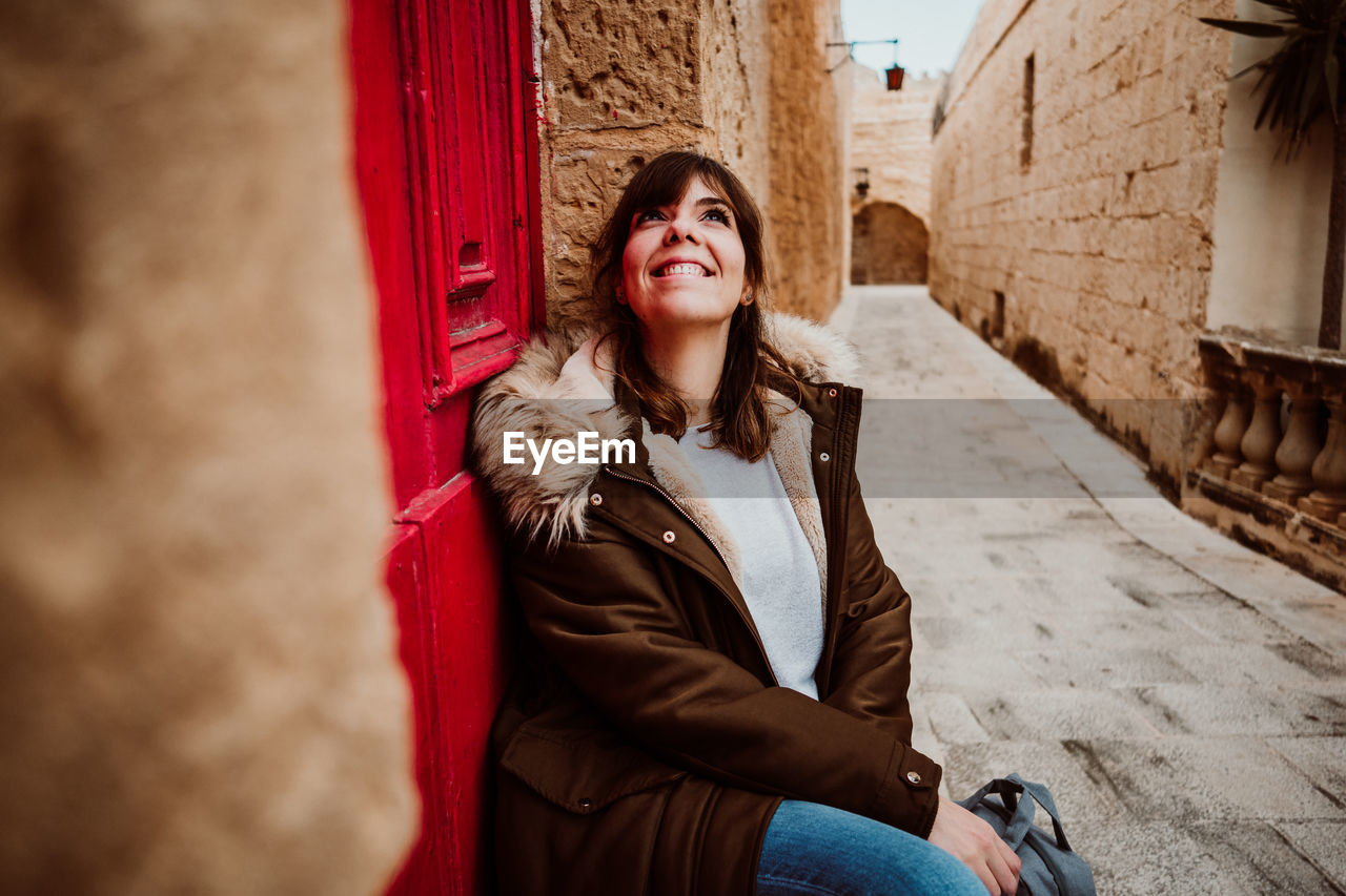 Full length of woman standing in alley amidst building