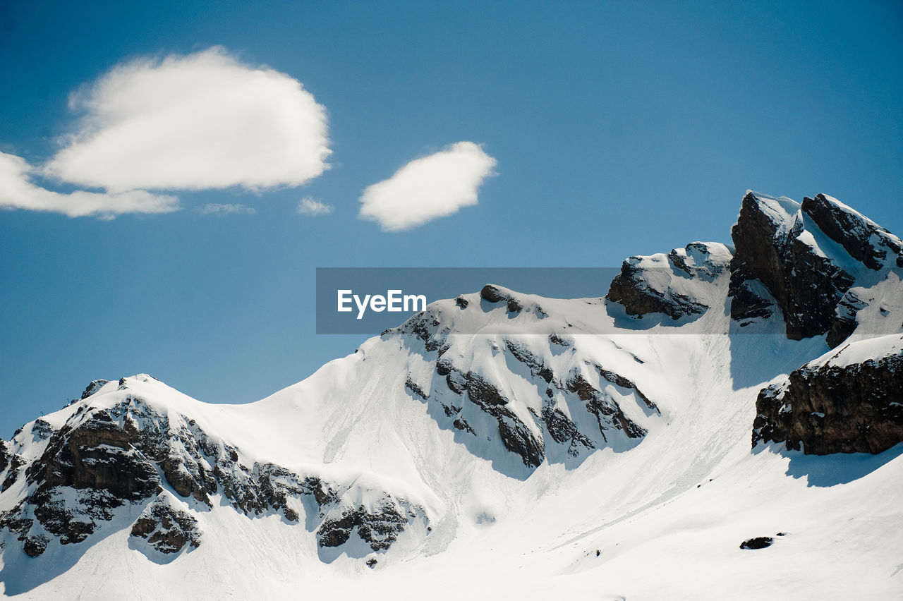 Snow covered mountain range against blue sky