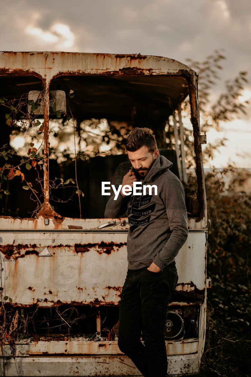 Man standing against abandoned bus