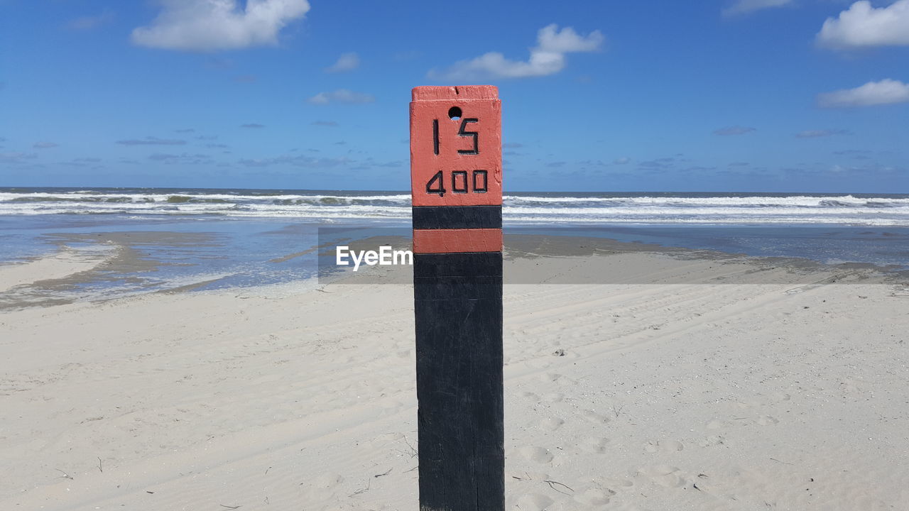 WARNING SIGN ON BEACH AGAINST SKY