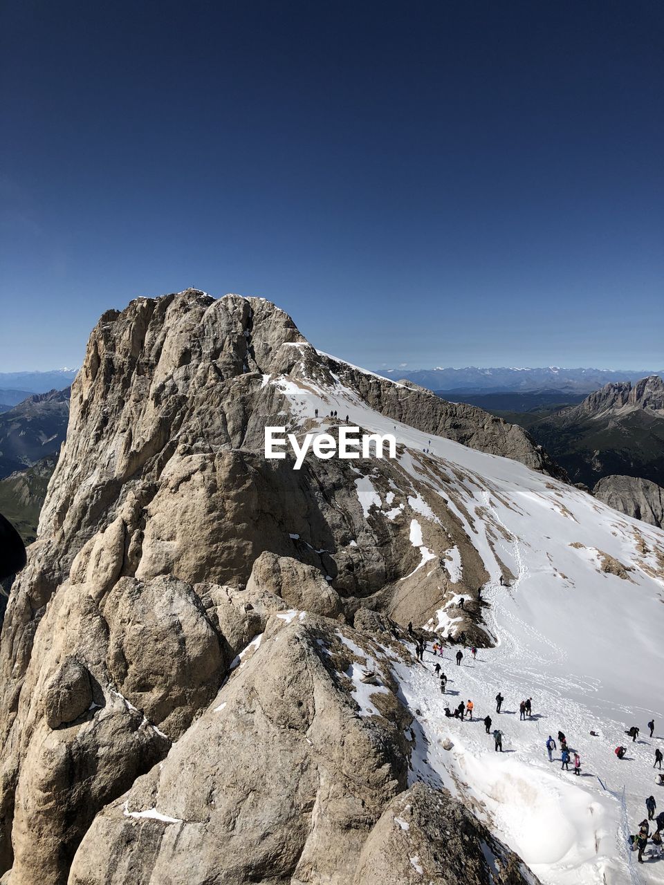 GROUP OF PEOPLE ON ROCK AGAINST MOUNTAIN RANGE