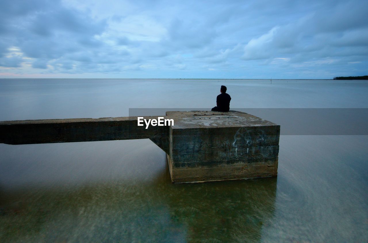 Rear view of man looking at sea against sky