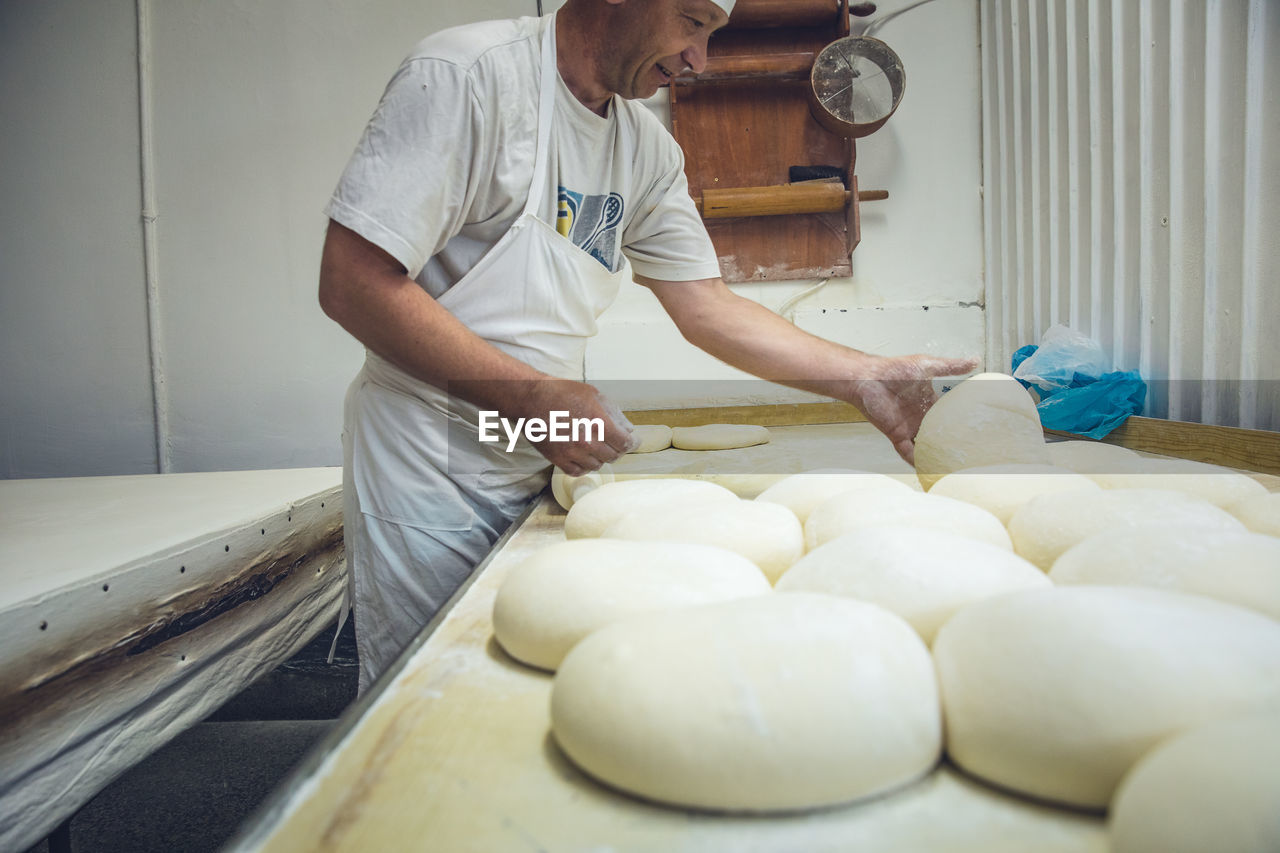 Man arranging rounds of dough at a bakery in belgrade, serbia