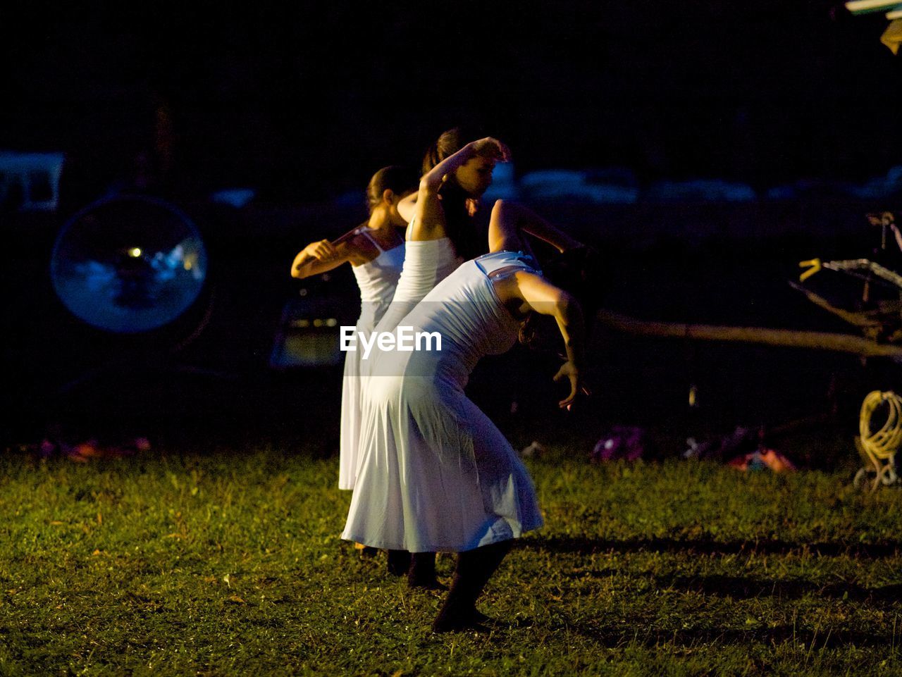 WOMAN STANDING ON FIELD DURING NIGHT