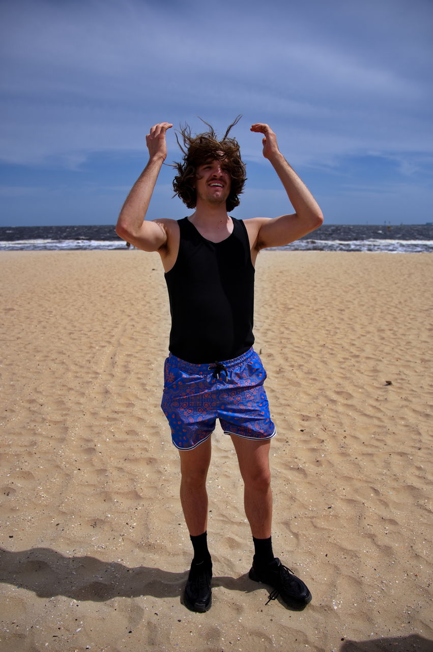 Young handsome man standing on a sandy beach