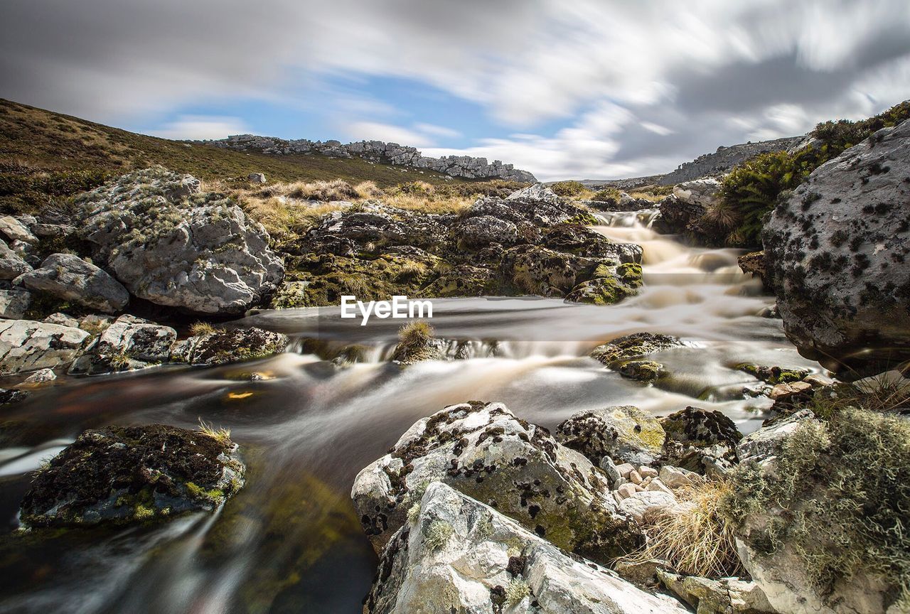 River flowing through rocks against sky
