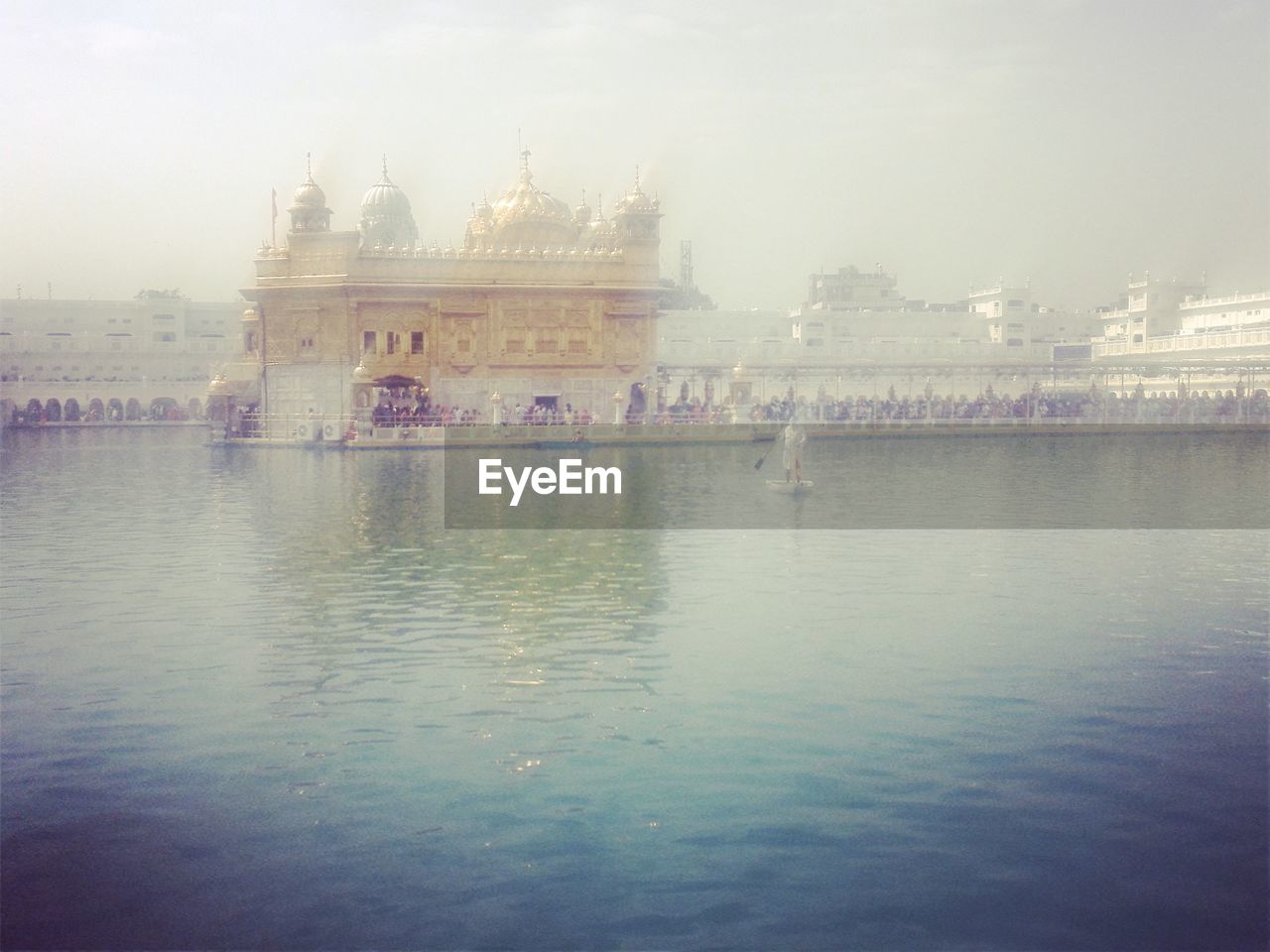 Building in front of river against sky during foggy weather