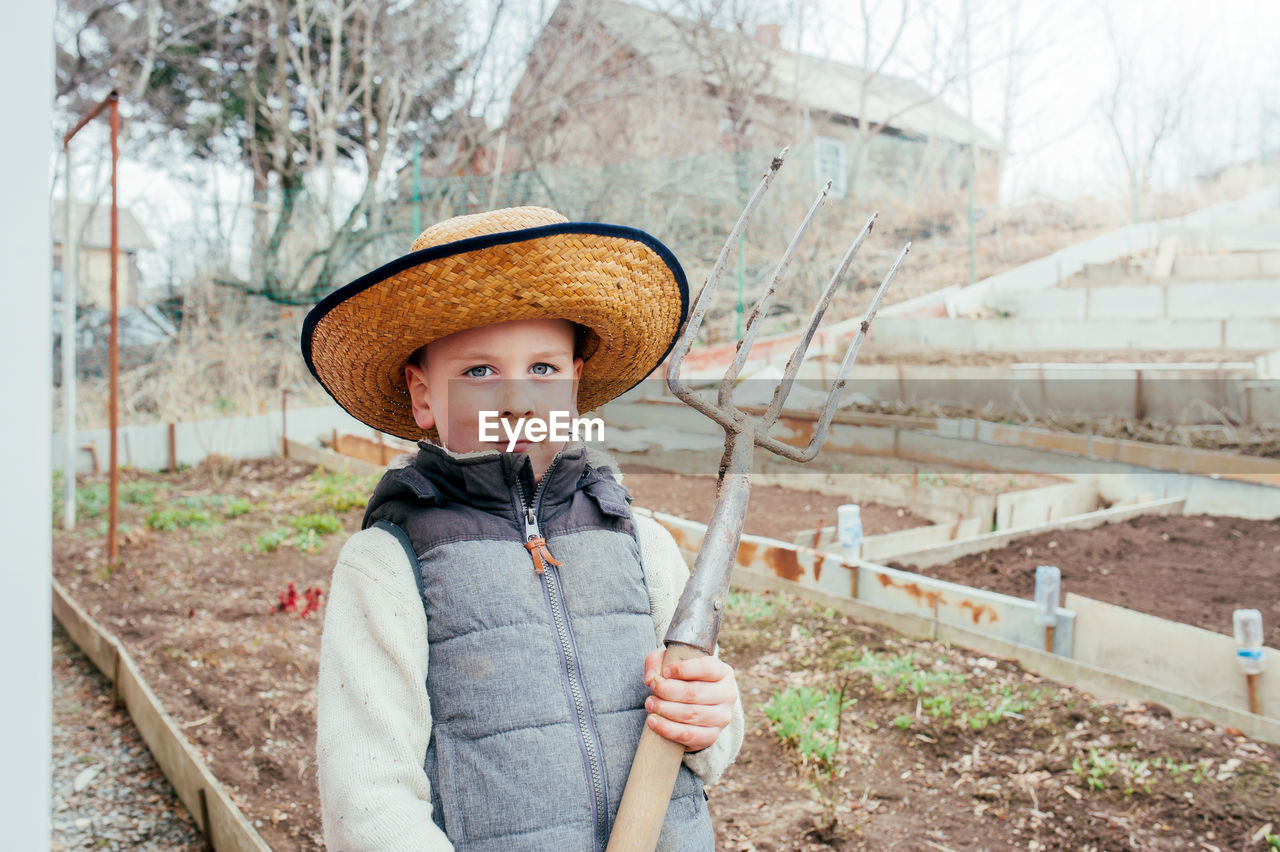 Cute light-skinned boy in a straw hat. activities for self-isolation in a country house.