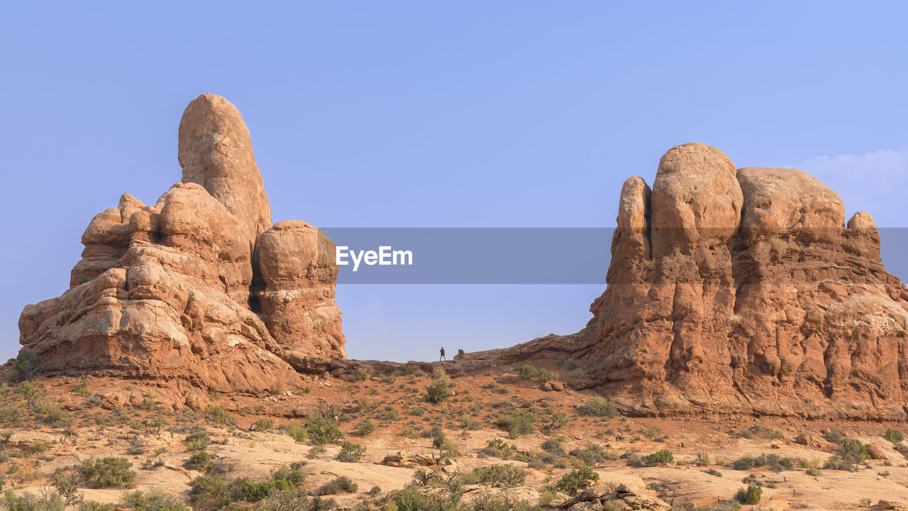 Hiker against blue sky at turret arch in arches national park