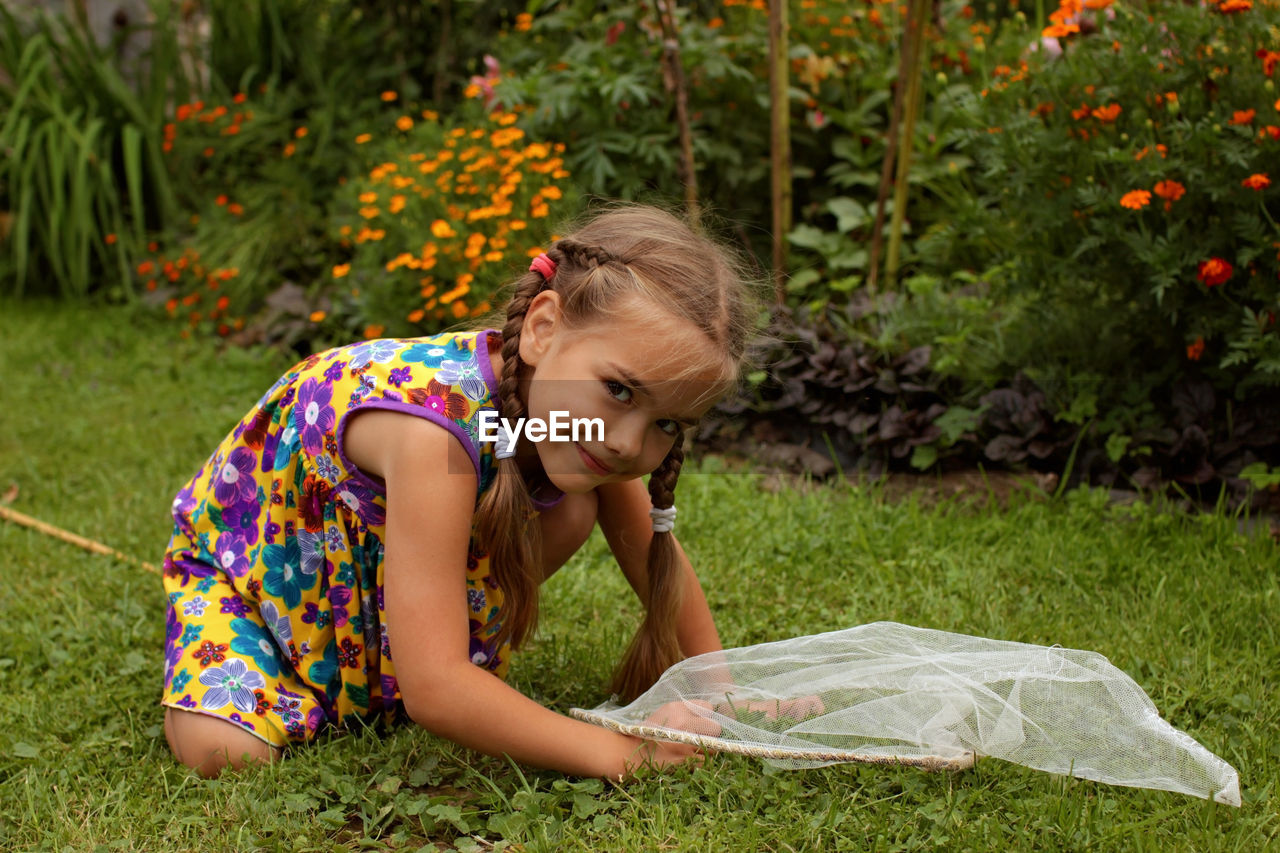 Portrait of cute girl catching insects at lawn