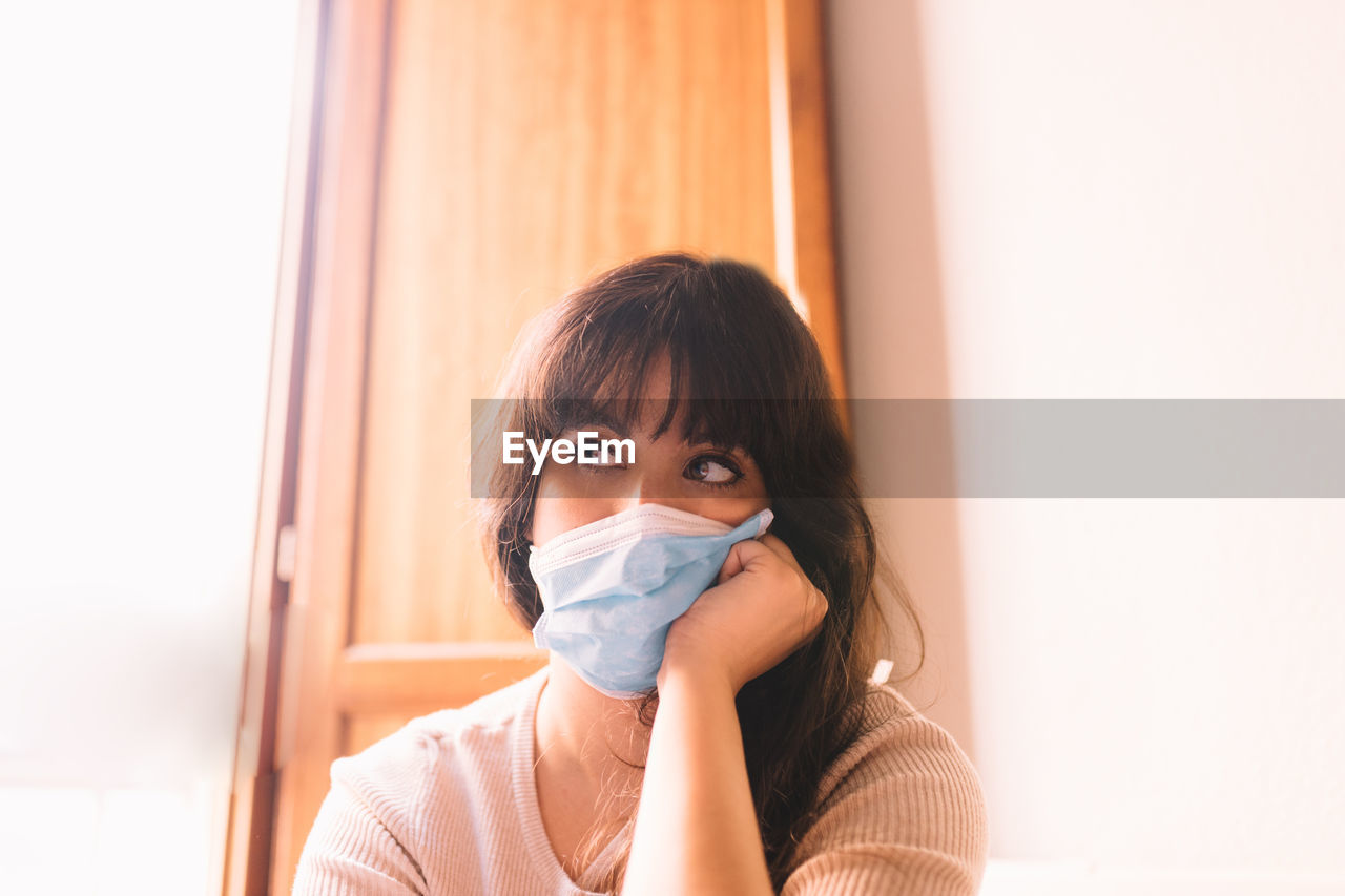 Woman wearing mask while sitting at home