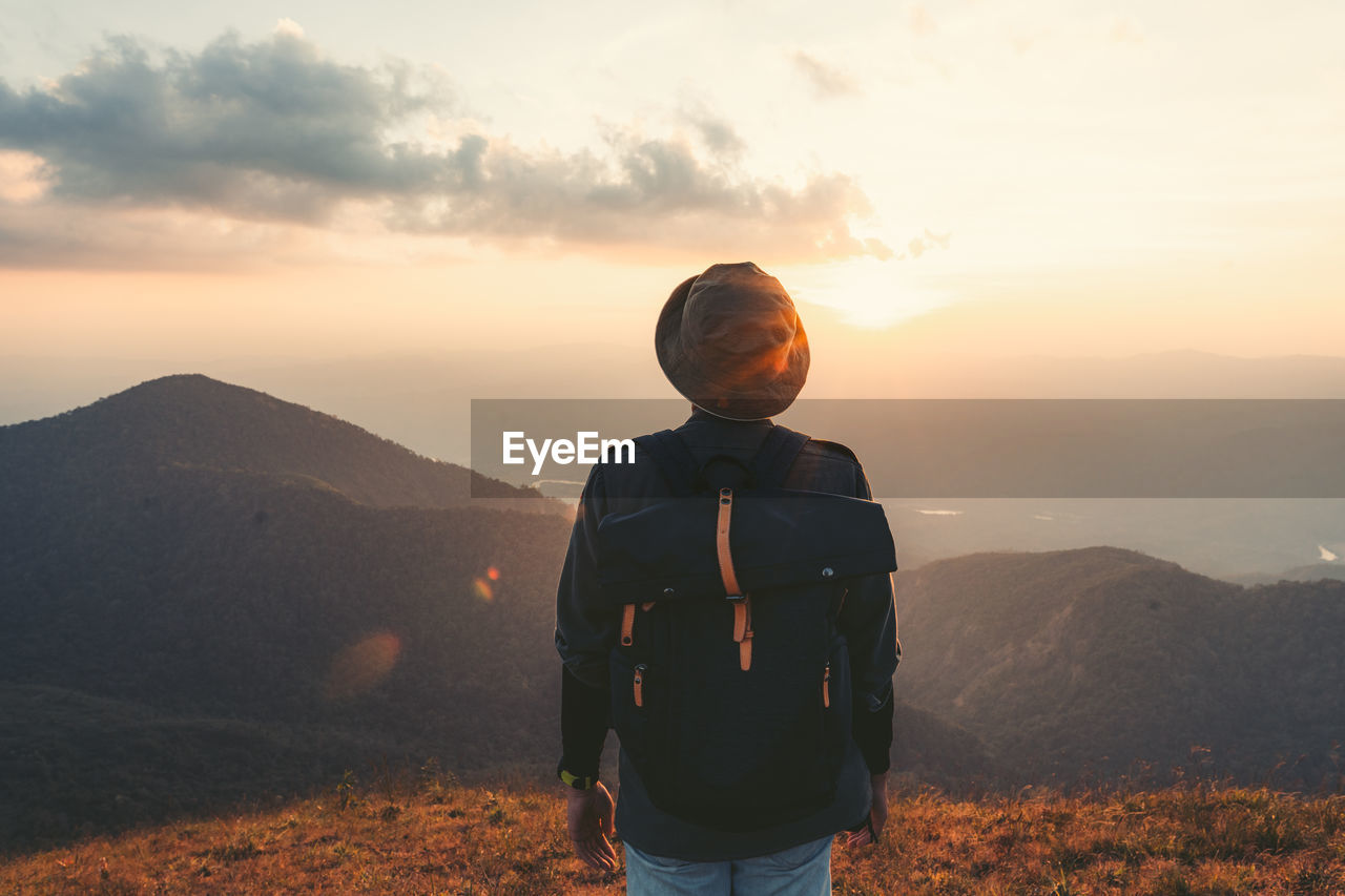 Rear view of man standing on mountain against sky