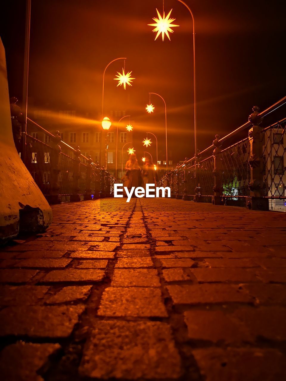 Illuminated street lights in city against sky at night