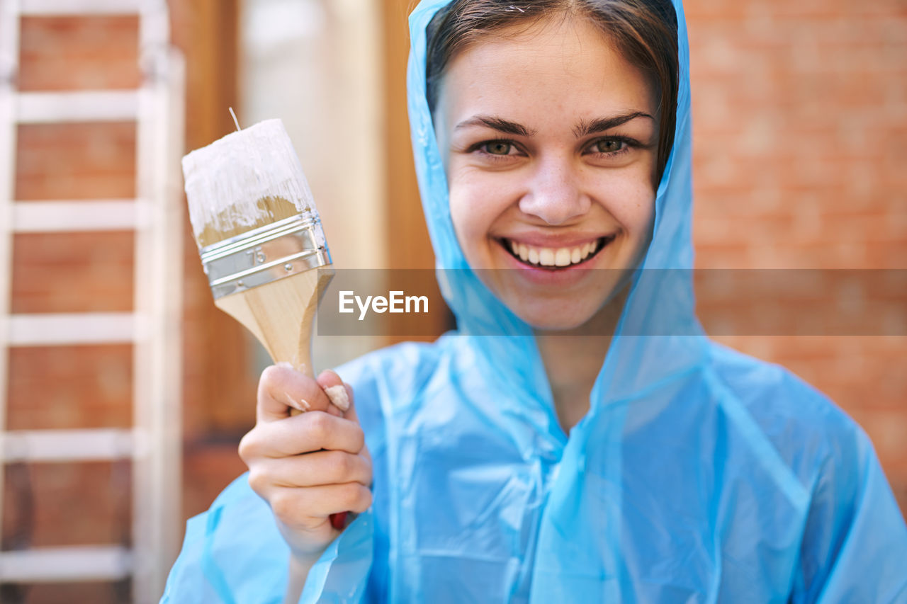 portrait of smiling young woman holding paintbrush