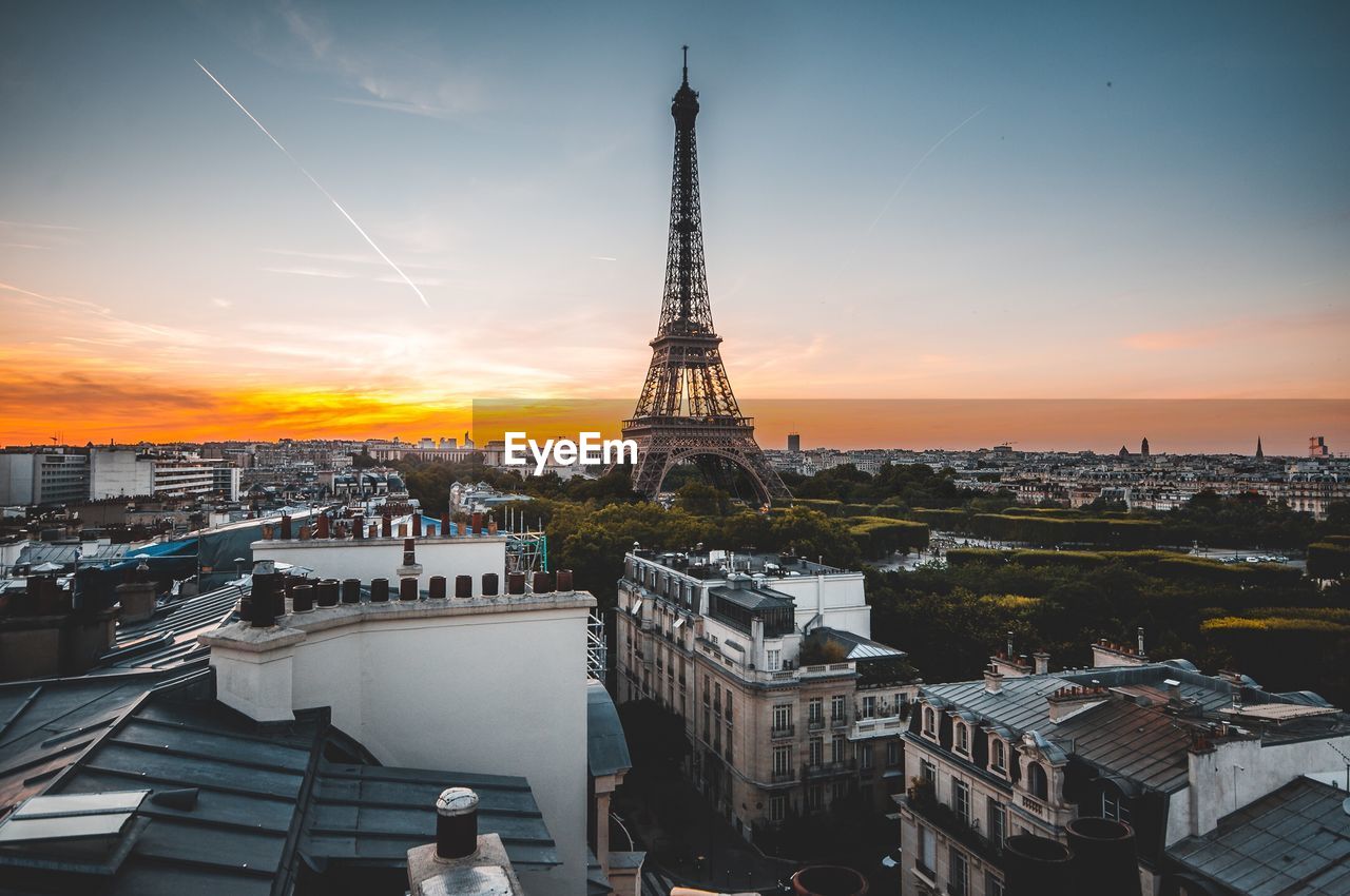 Eiffel tower in city against sky during sunset