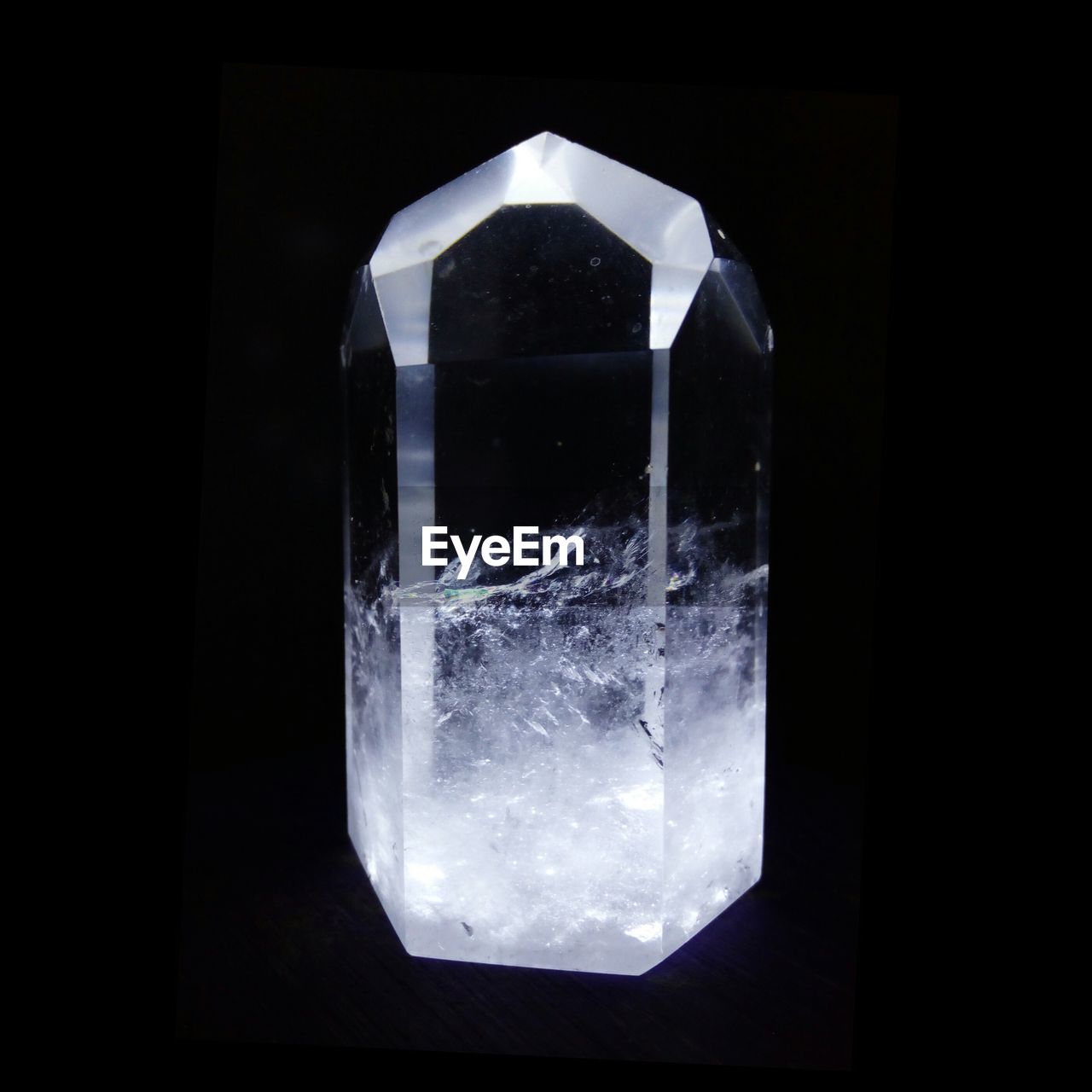 Close-up of  single quartz crystal point against black background