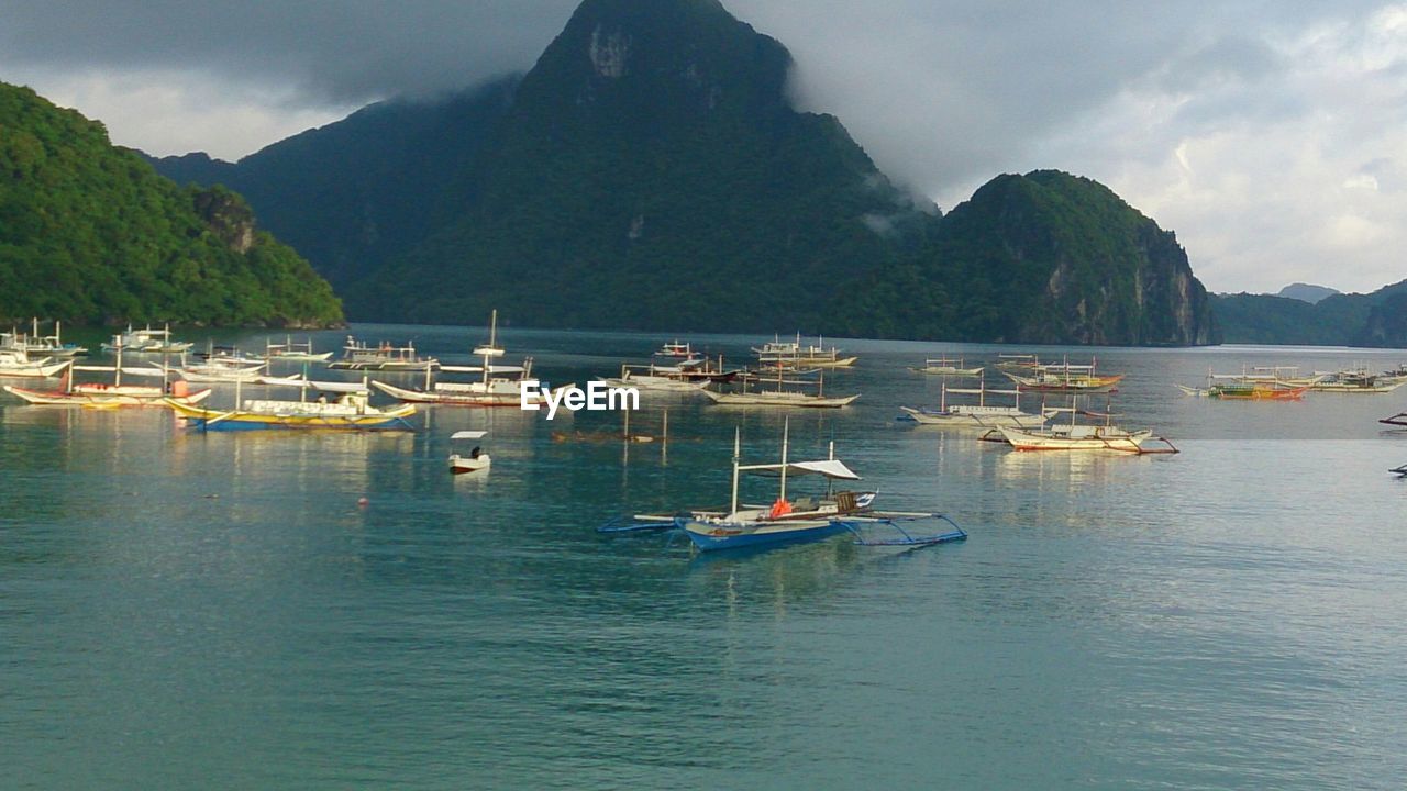 Boats in calm sea against mountain range